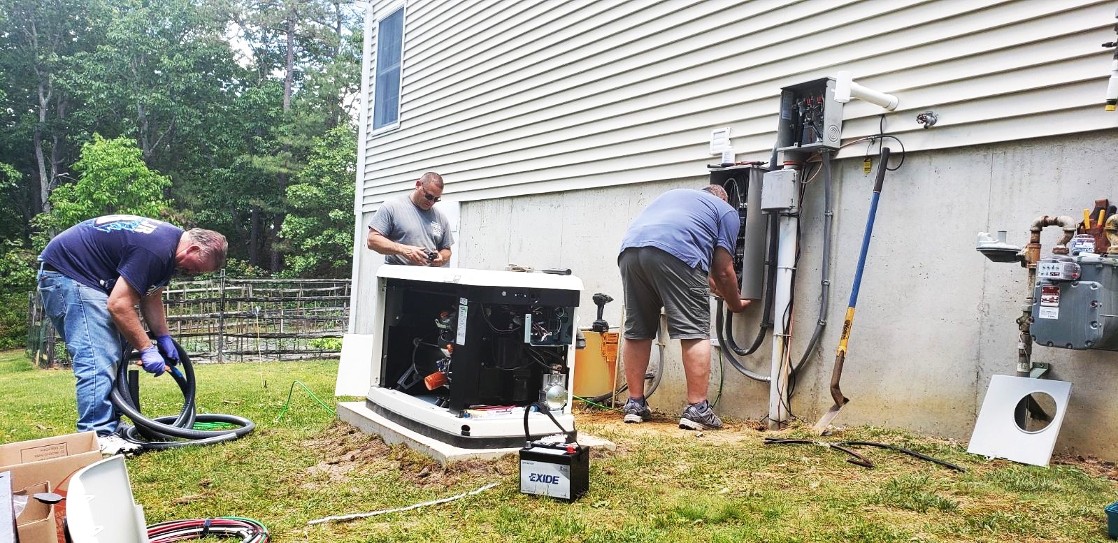 a photo of three men installing a generator next to the foundation of a house